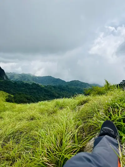 Trekking boots resting in tall grass looking out at green hills, Silent Valley